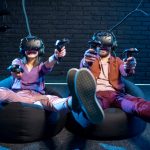 Man and woman shooting with gamepads while playing in virtual reality using VR headsets in the playing room