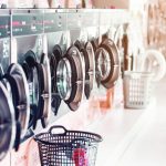 Row of industrial laundry machines in laundromat  in a public laundromat, with laundry in a basket , 
Thailand